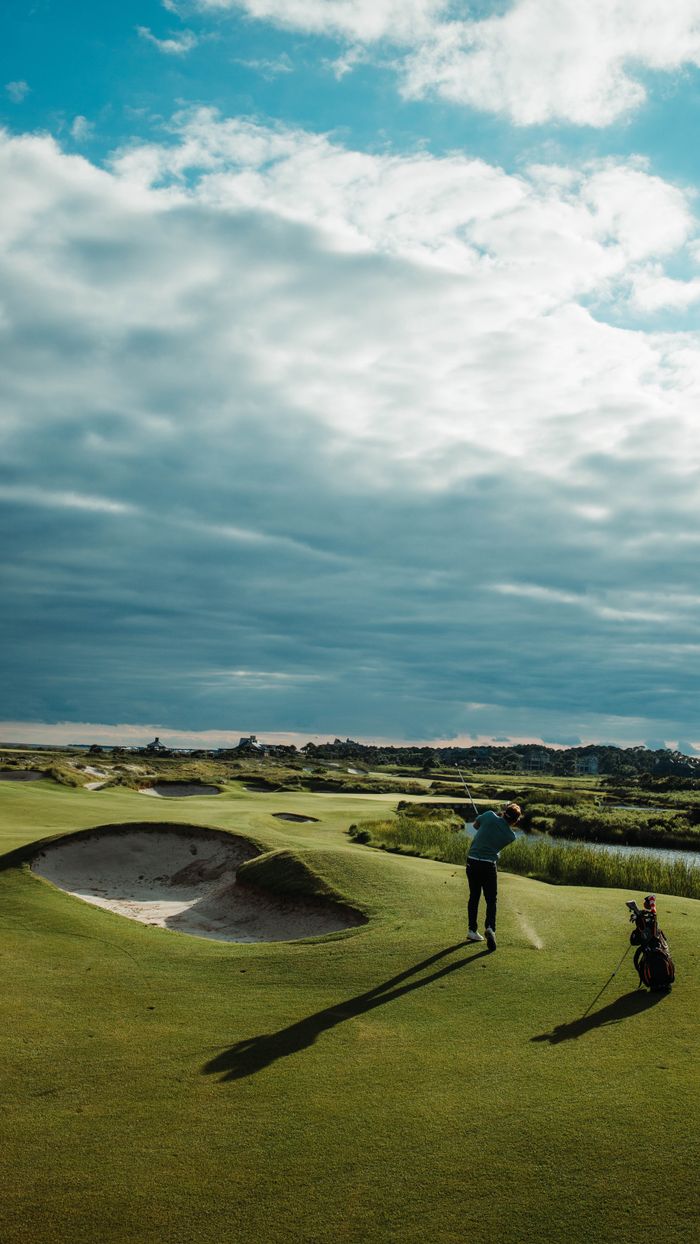 Golfer playing on scenic golf course, Kiawah Island, SC, with dramatic cloudy sky.